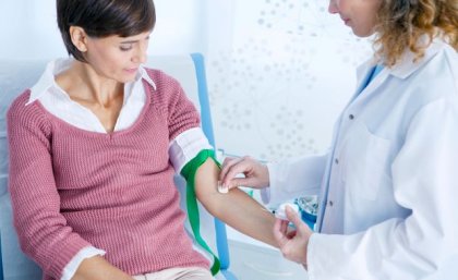 Healthcare worker preparing to take blood from middle aged woman 